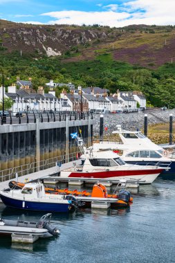 White houses on the coast and boats docked in the port of the city of Ullapool, Scotland clipart