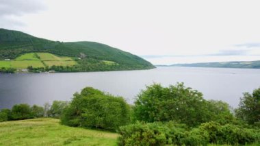 Loch Ness 'in yeşil manzarası, İskoçya' daki ağaçlar ve çayırlarla dolu gölü çevreleyen dağlar..