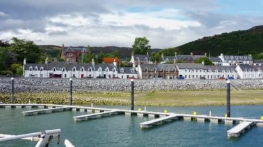 Kıyı kasabası Ullapool 'un panoramik manzarası tipik beyaz evleri ve İskoçya rıhtımına yanaşan rıhtımlarıyla