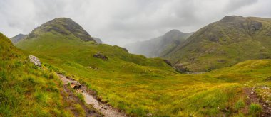 Dağların manzarası yeşil bir battaniye ve sis ile kaplı zirvelerde Glencoe, İskoçya