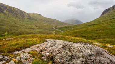 İskoçya 'daki Glencoe Vadisi' nde sis kaplı yeşil dağlar ve yürüyüş yolları