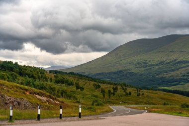 Glencoe, İskoçya 'daki yüksek dağlarla yeşil çayırlar arasında yol.
