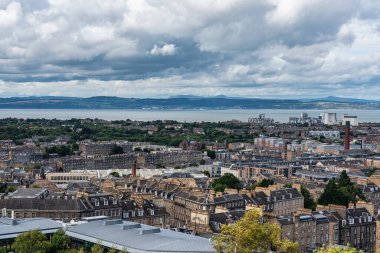 Edinburgh şehrinin panoramik manzarası, arka planda deniz ve iskan binaları, İskoçya.