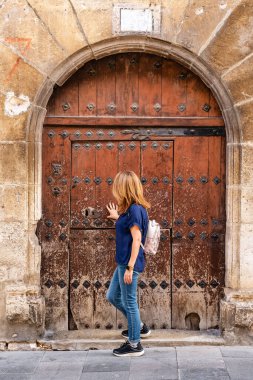 İspanya 'nın ortaçağ köyü Salvatierra' daki çok eski bir ahşap kapının yanındaki kadın.