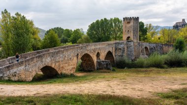 Burgos 'un Frias kentindeki eski ortaçağ taş köprüsünde yürüyen turist kadın..