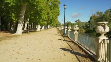 Uzun ağaçlı Tagus Nehri 'nin yanındaki patikada mavi gökyüzü ile yürüyen insanlar, Aranjuez