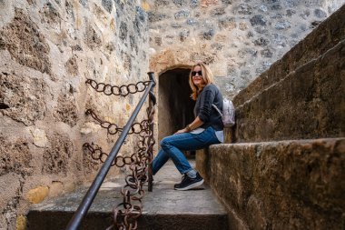 Frias, Burgos 'un ortaçağ duvarında taş bir bankta dinlenen turist kadın.