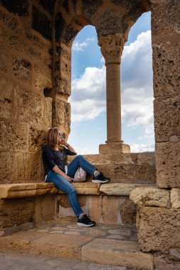 Burgos 'un Frias kasabasındaki bir ortaçağ taş penceresinden manzara seyreden turist kadın.