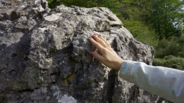 Büyülü bir ormanda, İspanya 'daki büyük bir kayanın dokusunda elini gezdiren bir kadın.