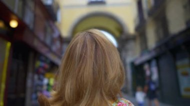 Madrid, İspanya 'daki Plaza Mayor' a giriş izni veren kemerli bir sokakta oturan turist kadın.