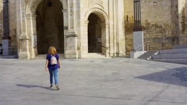 Turist kadın ana meydanda geziniyor ve İspanya 'nın Salvatierra kentindeki Bask köyündeki kiliseye bakıyor.