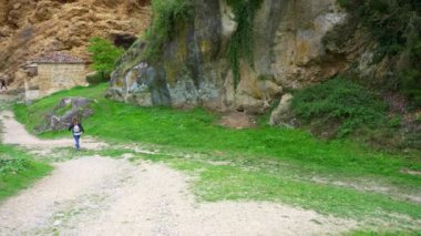 Ortaçağ kilisesinin yanında gezinen turist kadın kaya uçurumunun yanında, Tobera, Burgos