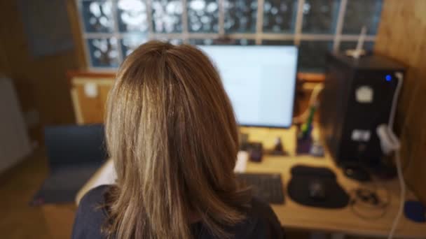彼女のワークステーションで働くコンピュータに彼女の背中を持つ女性とキーボードにタイピング — ストック動画