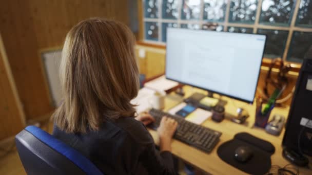 コンピュータや他のオフィス用品で自宅で働くために戻って彼女の背中の女性 — ストック動画