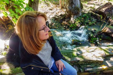 Patones de Arriba köyündeki tatlı su çeşmesinin yanında oturan turist kadın.