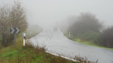 Yağmurlu bir günde kıvrımlı dağ yolu ve düşük görüş mesafeli kalın sis