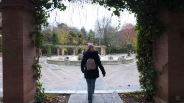 Turist kadın parkın caddelerinde geziniyor ve süslü çeşmelerin tadını çıkarıyor, Valladolid.