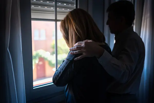 Man comforting his wife with depression and sadness and with his hand on her shoulder