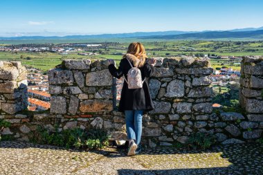 İspanya 'nın Trujillo kentinin ortaçağ duvarından eğilen turist kadın.