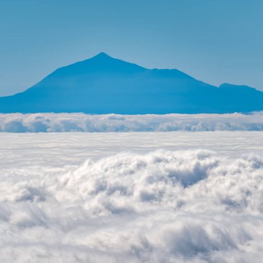 Okyanusun üzerindeki bulutlar denizi ve Kanarya Adası 'ndaki Tenerife adasındaki Teide volkanı silueti.