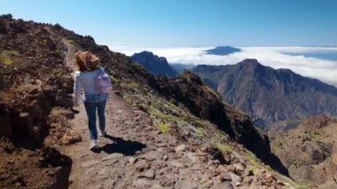 Dağın tepesindeki volkanik kayalar arasında yürüyen yürüyüşçü kadın, La Palma