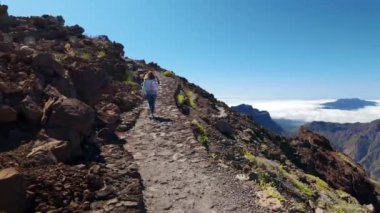 Dağın tepesindeki volkanik kayalar arasında yürüyen yürüyüşçü kadın, La Palma
