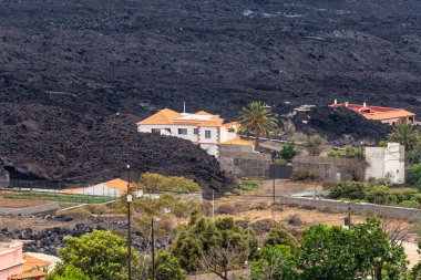 Volcanic lava emitted by the Cumbre Vieja volcano next to the houses on the island of La Palma, Canary Islands, Spain clipart