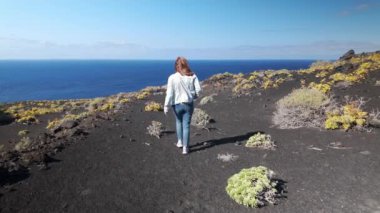 Kanarya Adaları 'ndaki La Palma adasının güneyindeki volkanik arazide geriye doğru yürüyen turist kadın.