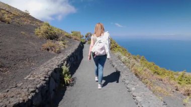 Kanarya Adaları 'ndaki La Palma Adası' nın güneyindeki volkanik dağ patikası boyunca geriye doğru yürüyen turist kadın.