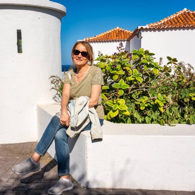 Santa Cruz de la Palma, Kanarya Adaları 'ndaki beyaz yüzlü koloni binalarının yanında dinlenen yaşlı turist kadın..