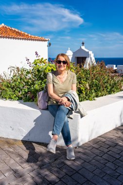 Santa Cruz de la Palma, Kanarya Adaları 'ndaki beyaz yüzlü koloni binalarının yanında dinlenen yaşlı turist kadın..