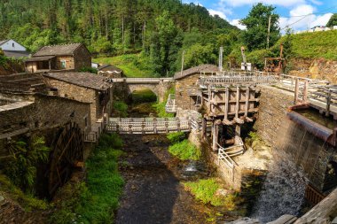 Set of old wooden mills that take advantage of the water of the river to grind grain, Taramundi, Asturias clipart