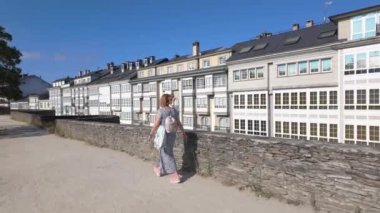 Sırtı dönük bir kadın turist, Dünya Mirası Bölgesi olan Lugo 'nun Roma duvarından geçiyor.