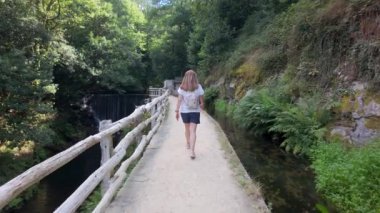 Asturias, Taramundi 'deki bir baraja giden yol boyunca yürüyen bir turist kadın..