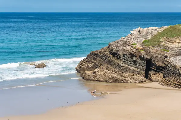 stock image Man sitting on a chair on the beach of the cathedrals while relaxing and enjoying the sea, Galicia, Spain