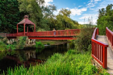 A tourist woman leaning over a bridge that crosses the Arnoia River as it passes through the town of Allariz, Galicia clipart