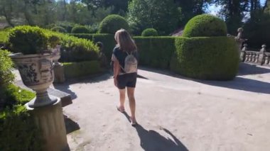 Sırtı dönük bir kadın İspanya 'daki Pazo de Oca sarayının büyüleyici Fransız tarzı bahçelerinde yürüyor.