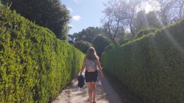 Sırtı dönük bir kadın İspanya 'daki Pazo de Oca sarayının büyüleyici Fransız tarzı bahçelerinde yürüyor.