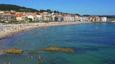 Güneşli bir yaz gününde Sanjenjo 'nun devasa plajının havadan görünüşü ve turistlerle dolu, Pontevedra, İspanya