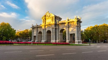 Alcala Kapısı gün doğumunda ağaçlardan gelen güneş ışınlarıyla görüldü, Madrid, İspanya.