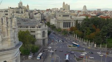 Plaza de Cibeles, yeni bir günün şafağında İspanya 'nın Madrid şehrinde çevre sokaklardan geçen araçlarla.