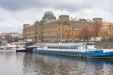 Prag kentindeki Vltava Nehri kıyısında resmi binalar ve turist tekneleri