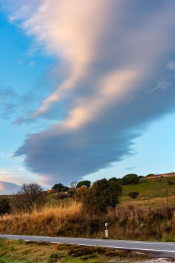 Golden clouds at sunset over the mountain road of the Sierra de Guadarrama, Madrid clipart