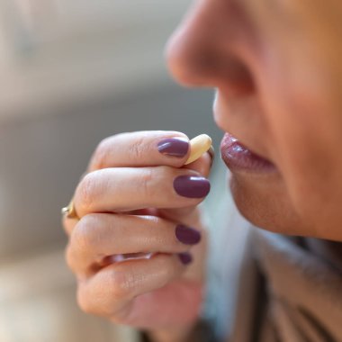 Kadının eli ağzının yanında hap tutuyor. Almak ve hastalığını iyileştirmek için.