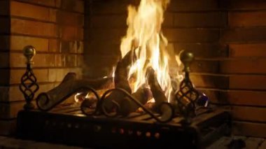 Tuğla şöminede yanan ateş, yakın. Şöminede ateş, odun, renkli alevler ve bokeh ışıkları. Siyah bulanık arkaplanda büyük bir alev