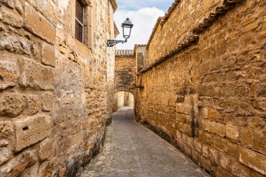 Baeza, Jaen, İspanya sokaklarında çok eski taş duvarlar ve ortaçağ kemerleri olan dar bir sokak.