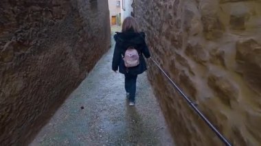 Orta çağ köyü Calaceite, Teruel, Aragon 'da dar sokaklarda gezen kadın turist.