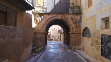 Çok eski evleri ve koridorun tepesinde küçük kiliseleri olan taş kemerleri olan pitoresk bir sokak. Calaceite, Teruel.
