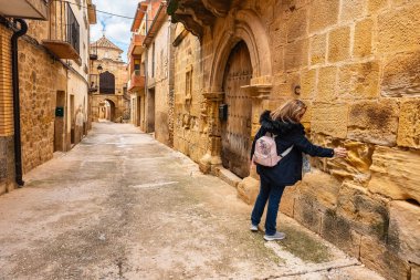 Kretas, Teruel, Aragon kentinin tarihi binalarının ortaçağ taşına dokunan turist kadın.