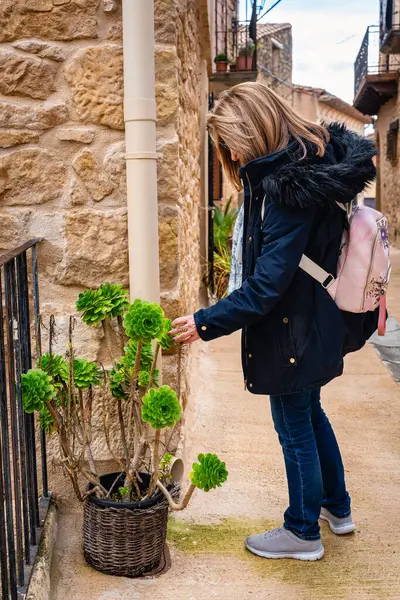 Cretas, Teruel, Matarrana köyünün sokaklarını süsleyen bitkilere dokunan kadın.